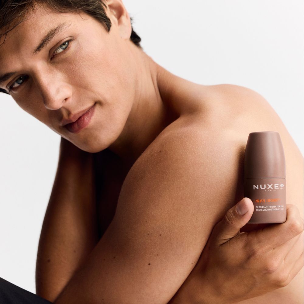 Un uomo tiene un roll-on deodorante Nuxe Men Protezione 24H vicino all'ascella.