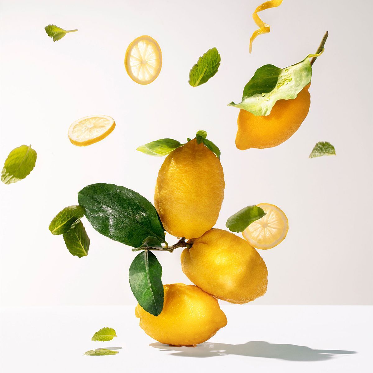 Limoni, foglie e fette fluttuanti su sfondo bianco. Composizione decorativa.