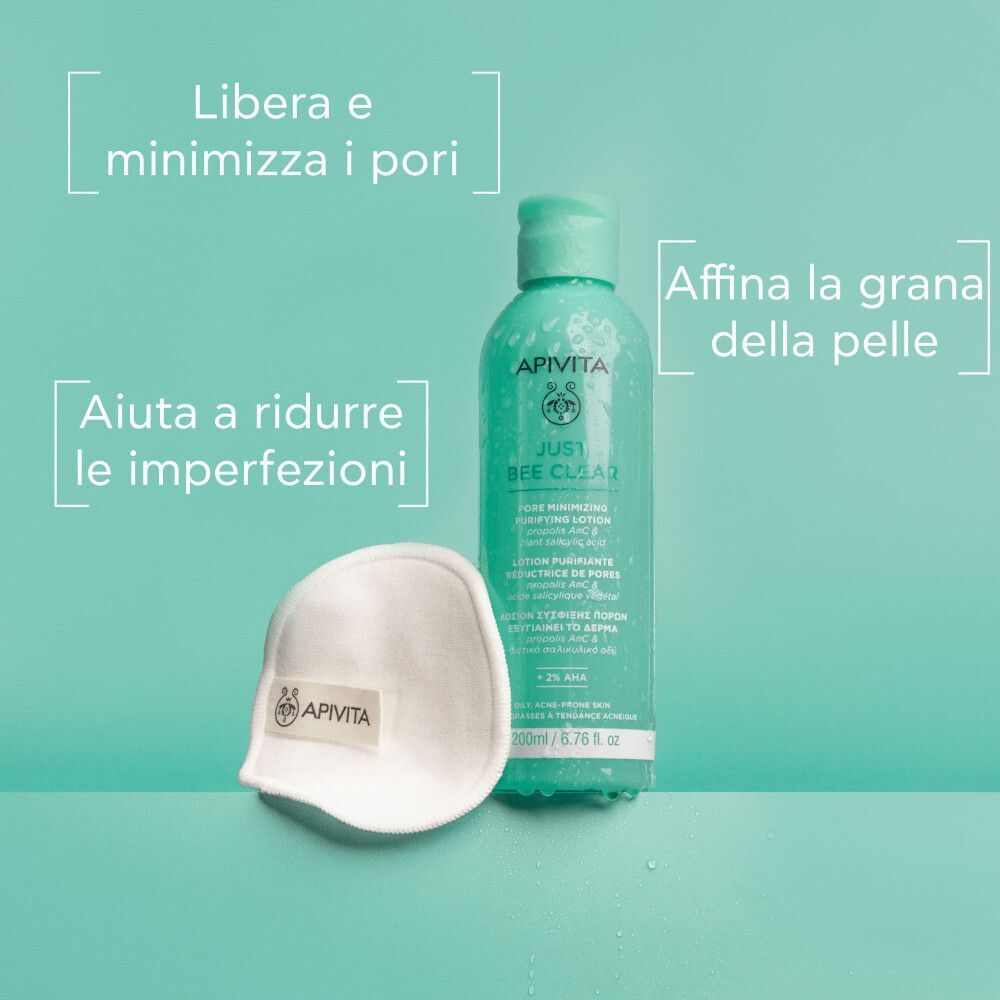 Lozione Apivita Just Bee Clear accanto a un dischetto di cotone. Testo: 'Libera e minimizza i pori', 'Aiuta a ridurre le imperfezioni'.