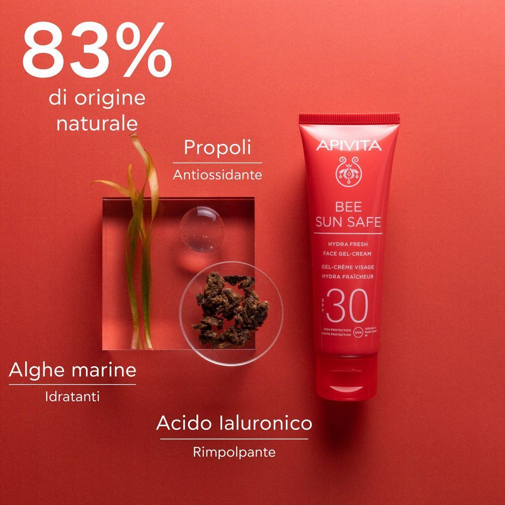 Tubo rosso APIVITA Bee Sun Safe Hydra Fresh Face Gel-Cream SPF 30 accanto a ingredienti come propoli e alghe.