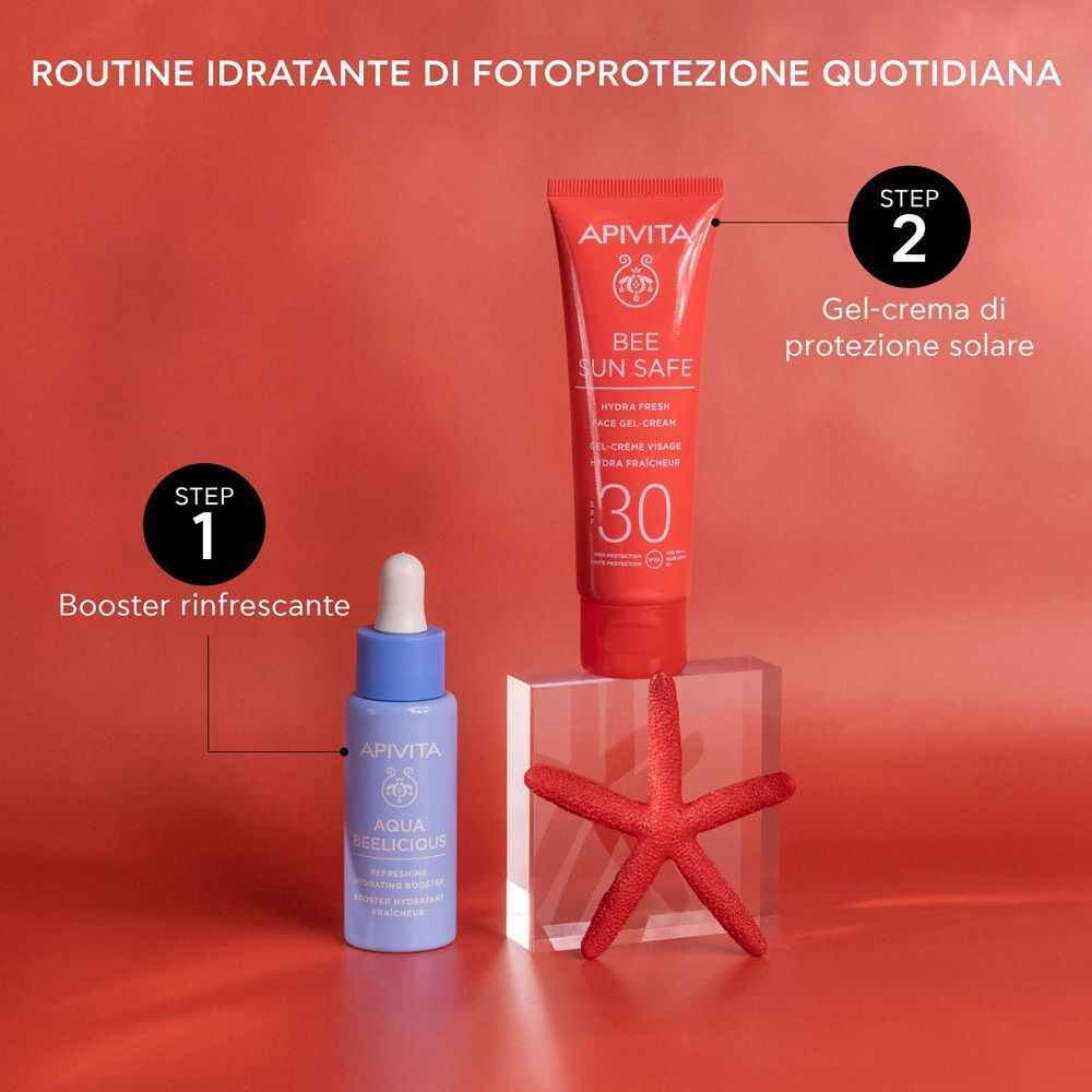 Tubo rosso APIVITA Bee Sun Safe Hydra Fresh Face Gel-Cream SPF 30 e un booster blu su blocchi acrilici.