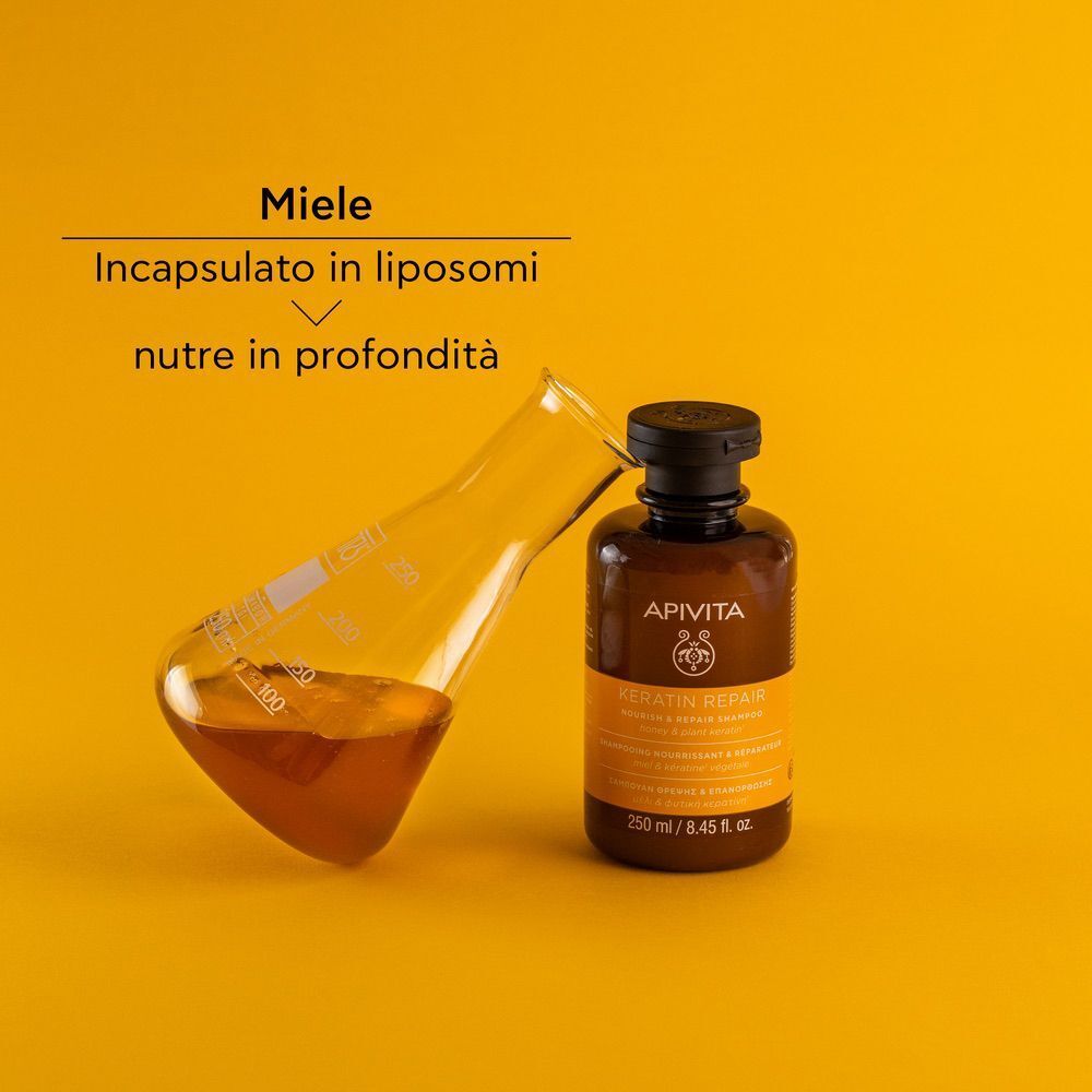 Shampoo Keratin Repair APIVITA accanto a un becher da laboratorio con miele.