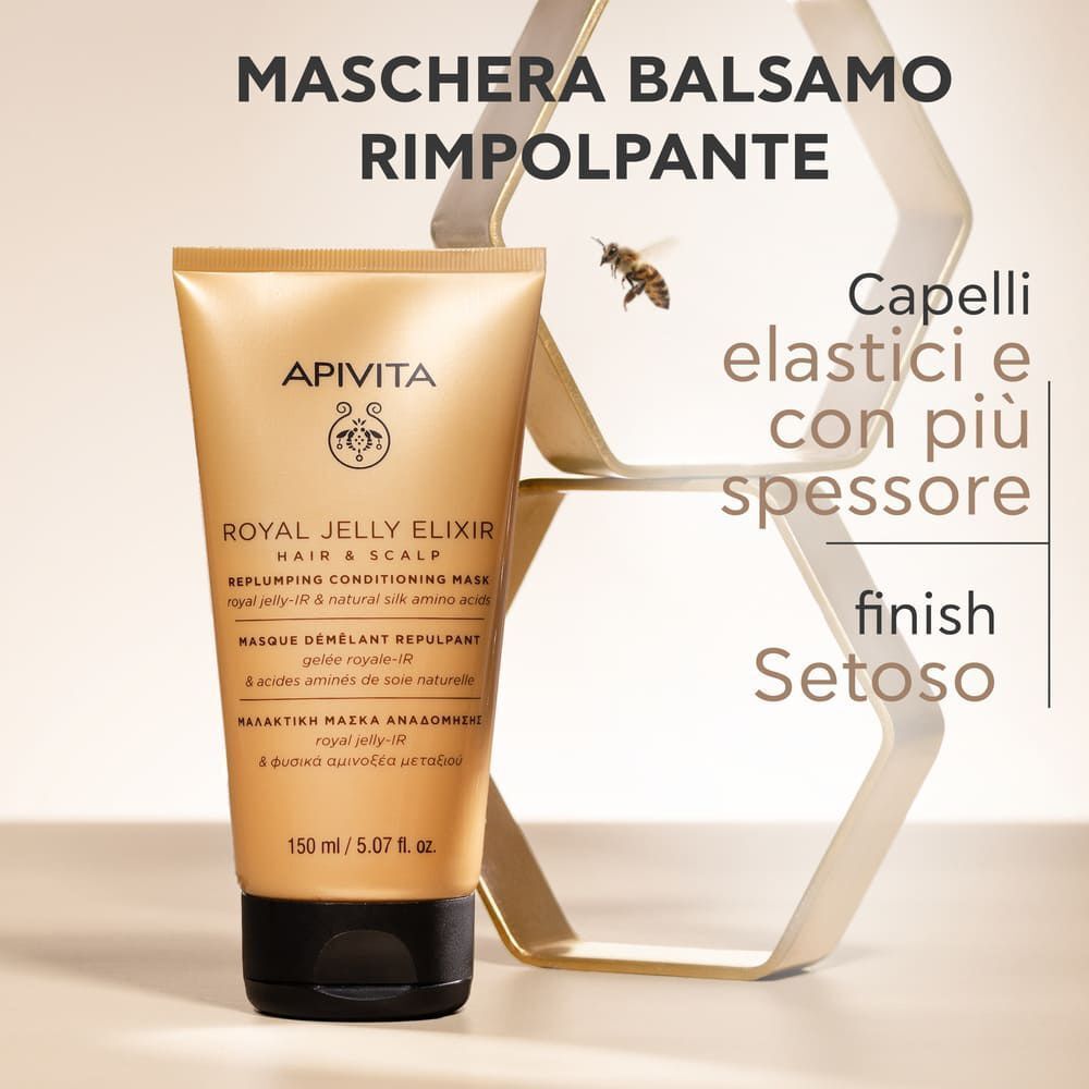 Tubo dorato Apivita Royal Jelly Elixir Maschera Balsamo Rimpolpante accanto a una struttura dorata astratta con un'ape.