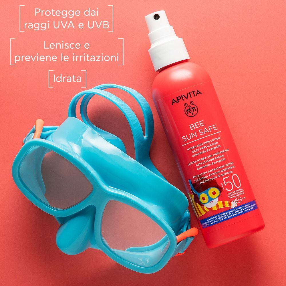 Flacone spray rosso protezione solare SPF 50 accanto a una maschera da nuoto blu.