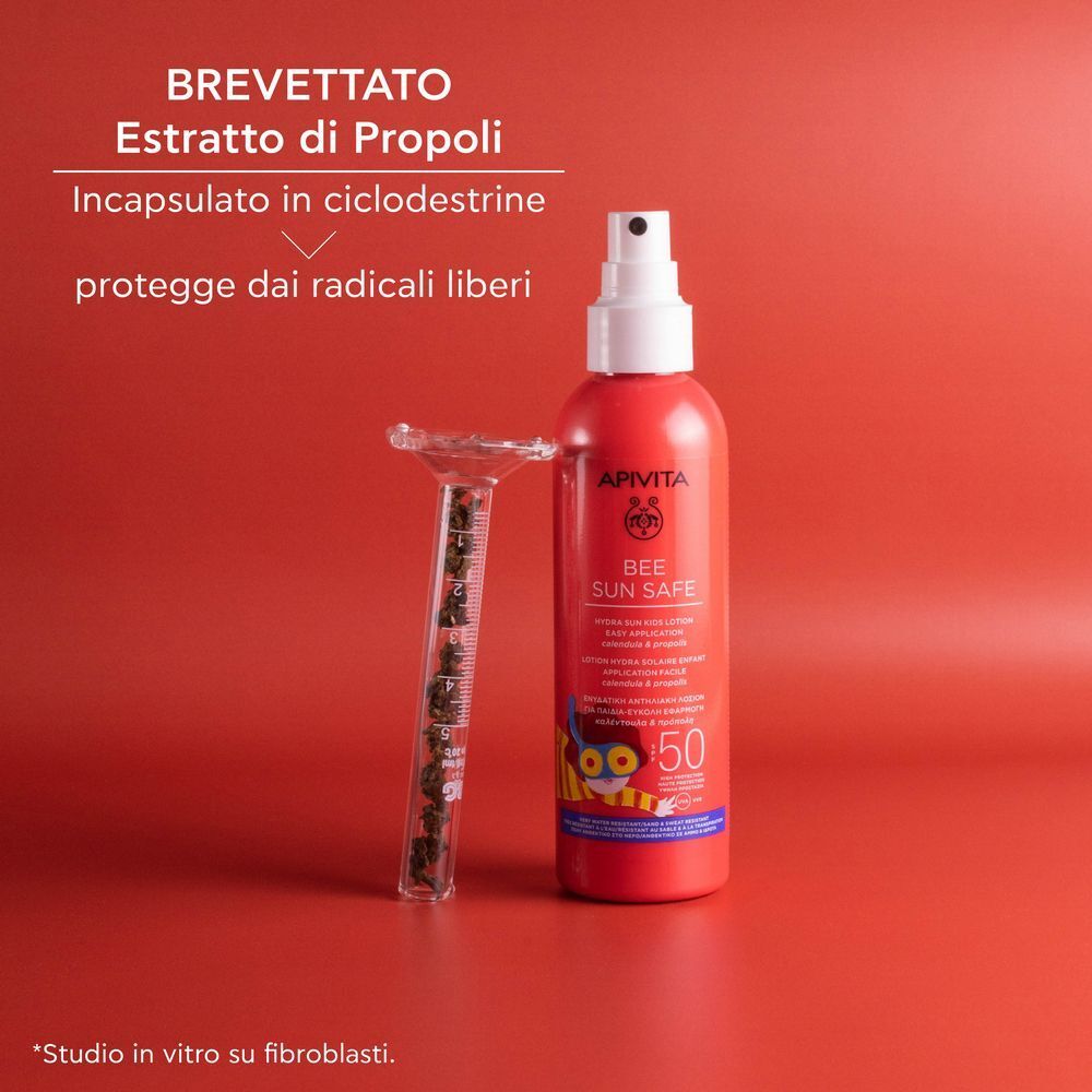 Flacone spray rosso protezione solare SPF 50 accanto a un tubo di vetro con estratto di propoli.