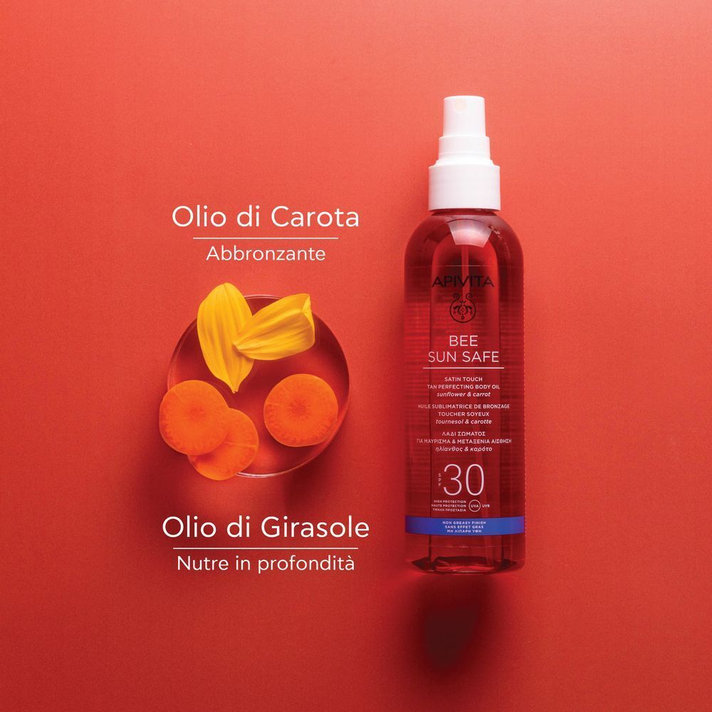 Olio solare APIVITA SPF30 accanto a estratti di olio di carota e girasole. Flacone rosso con spray.