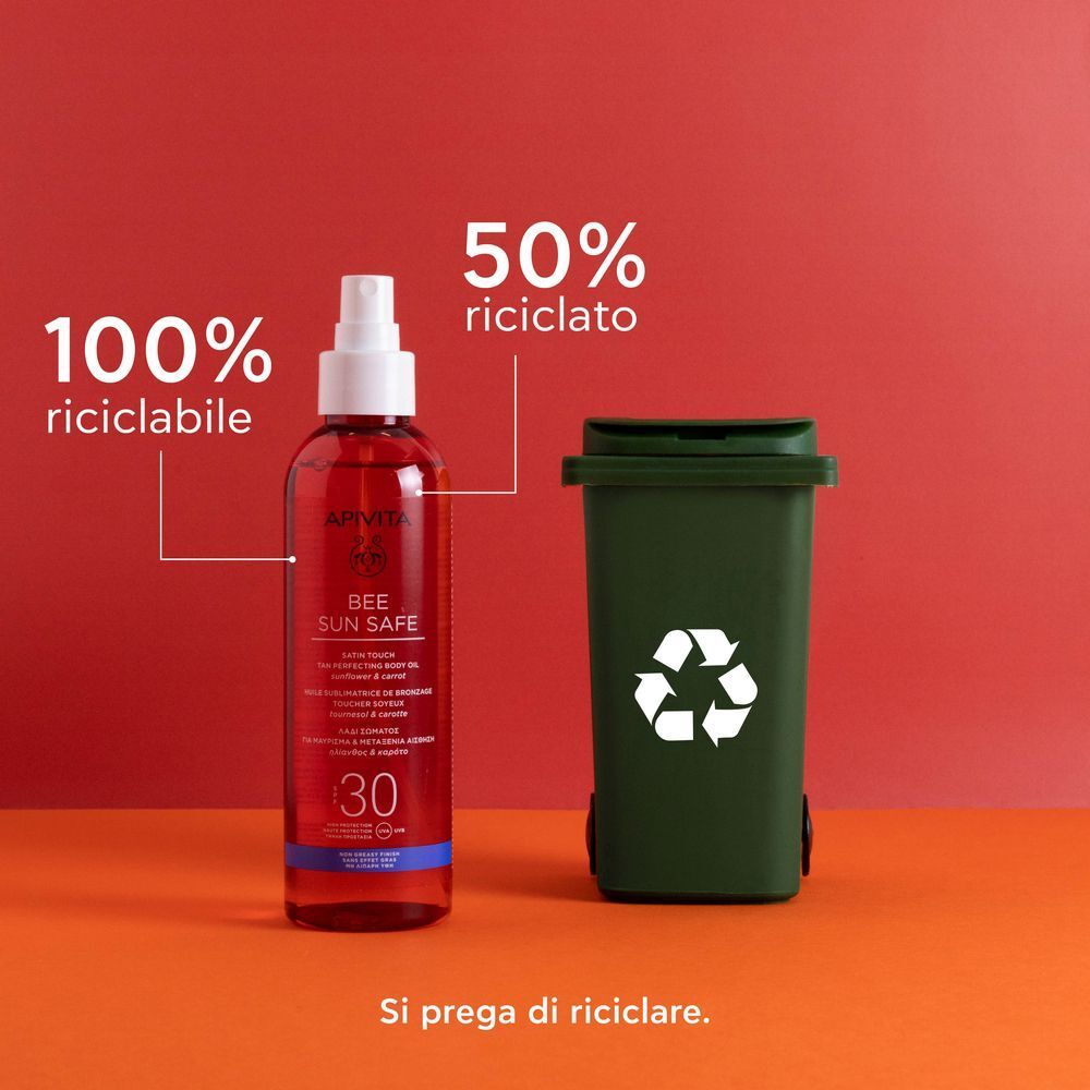 Olio corpo abbronzante APIVITA SPF30 accanto a un bidone della spazzatura verde. 100% riciclabile, 50% riciclato.