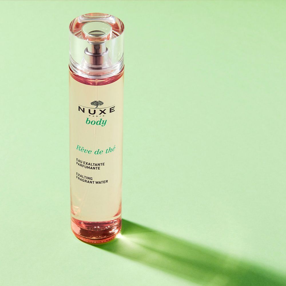 Un flacone Nuxe Rêve De Thé Eau Exaltante parfumante su sfondo verde.