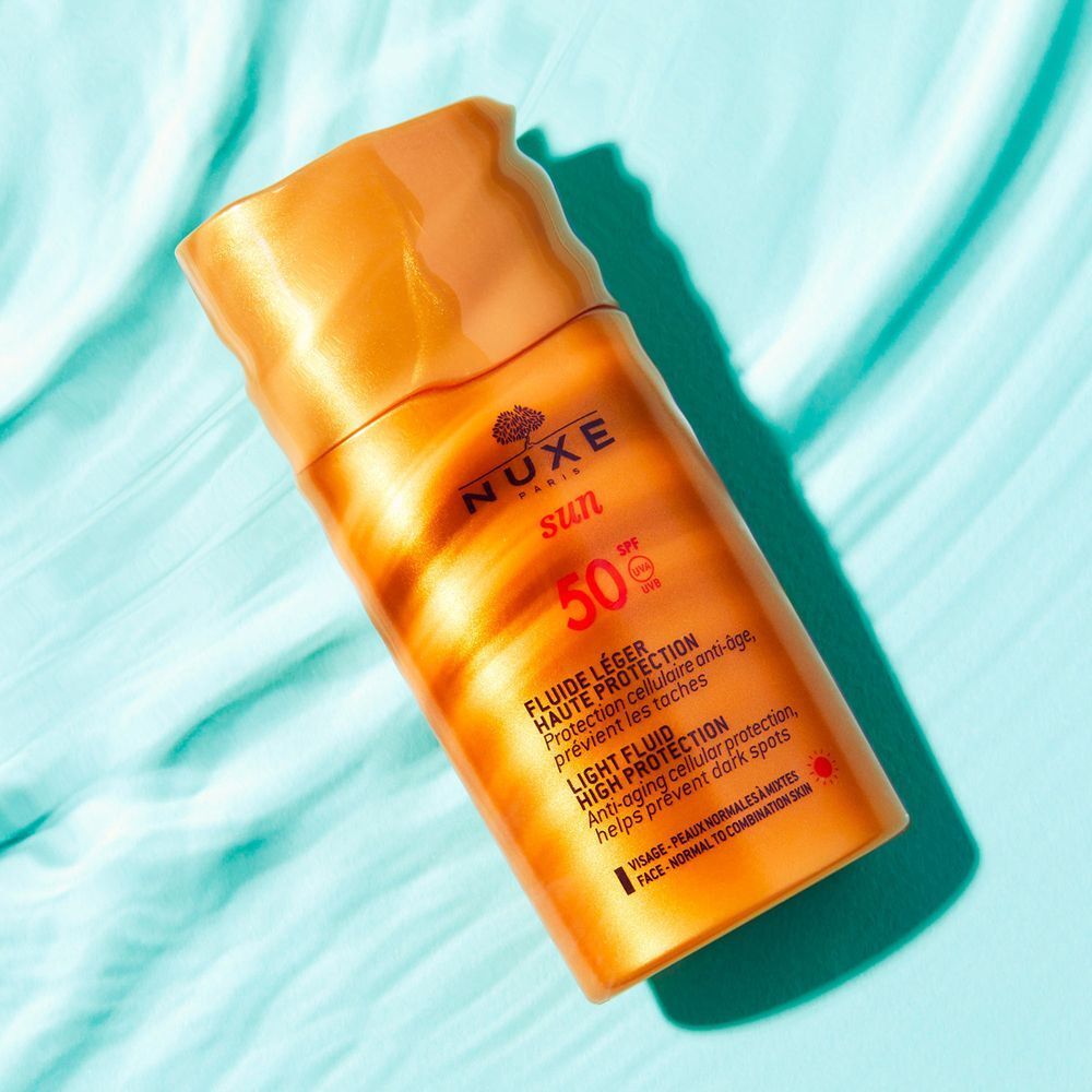 Flacone Nuxe Sun Fluido Leggero Alta Protezione SPF 50 su sfondo acquatico.