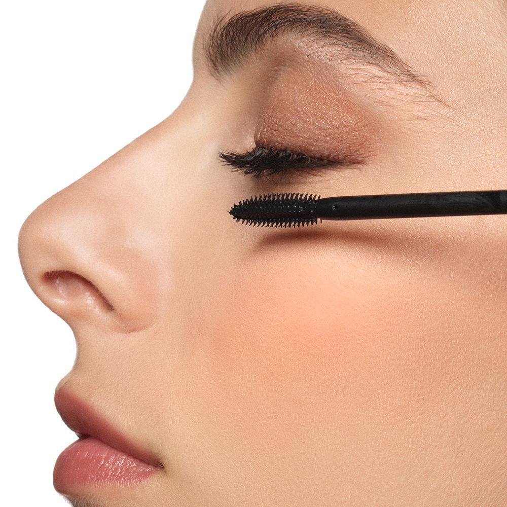 Primo piano di una donna che applica mascara nero sulle ciglia.