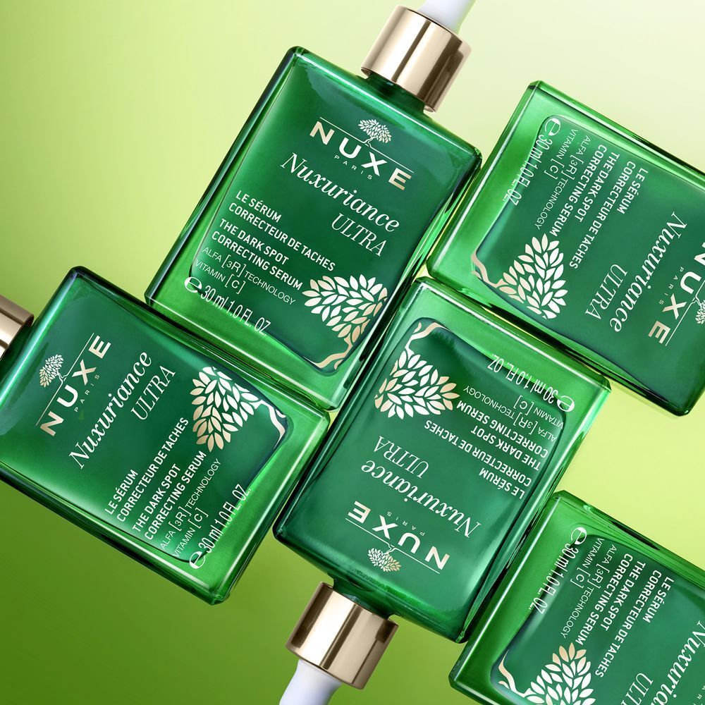 Molti flaconi in vetro verde Nuxe Nuxuriance Ultra siero, visti dall'alto.