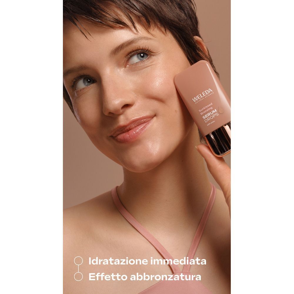 Una donna tiene un flacone di WELEDA Sunkissed Bronzing Serum Drops.