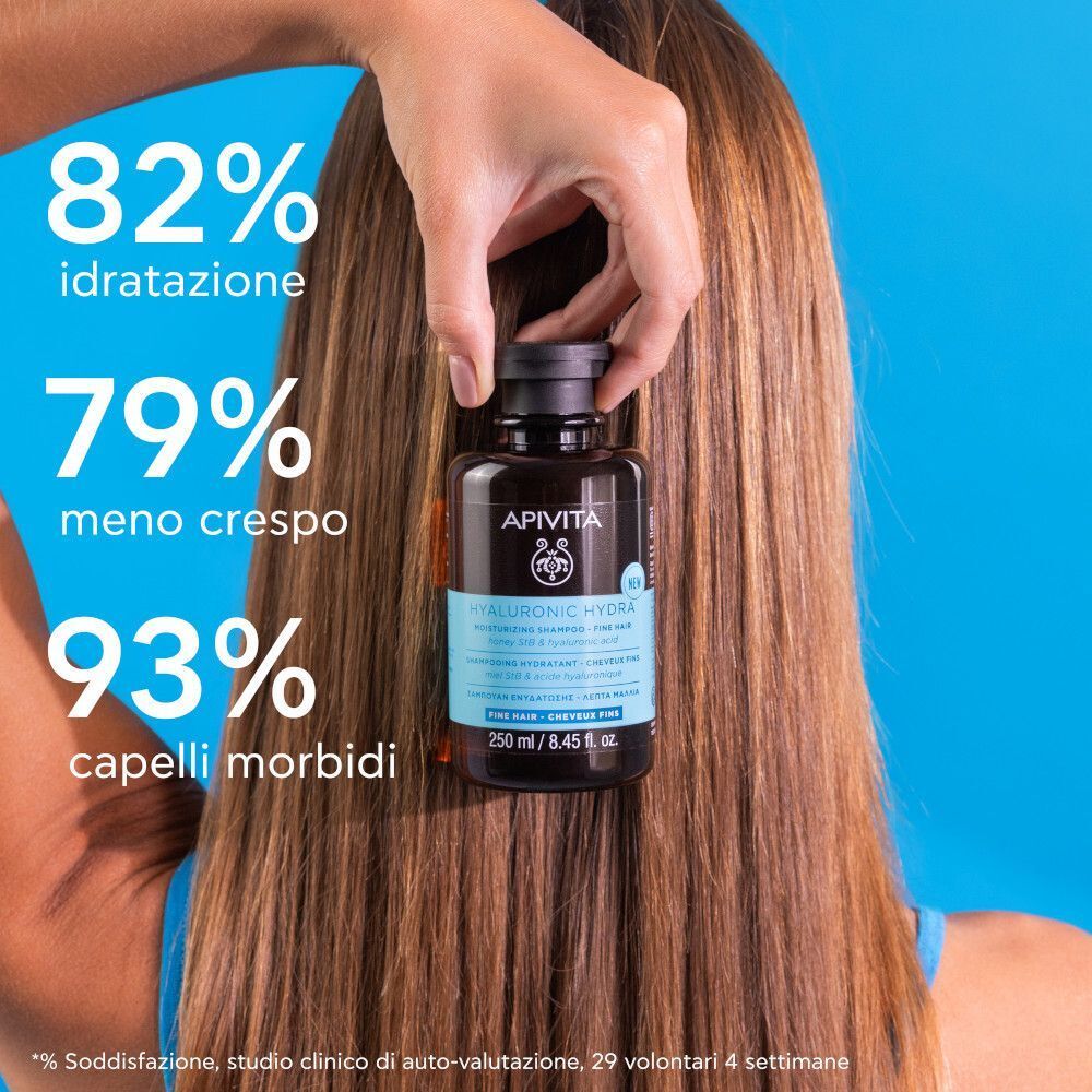Donna con capelli lunghi che tiene una bottiglia di shampoo idratante APIVITA Hyaluronic Hydra.