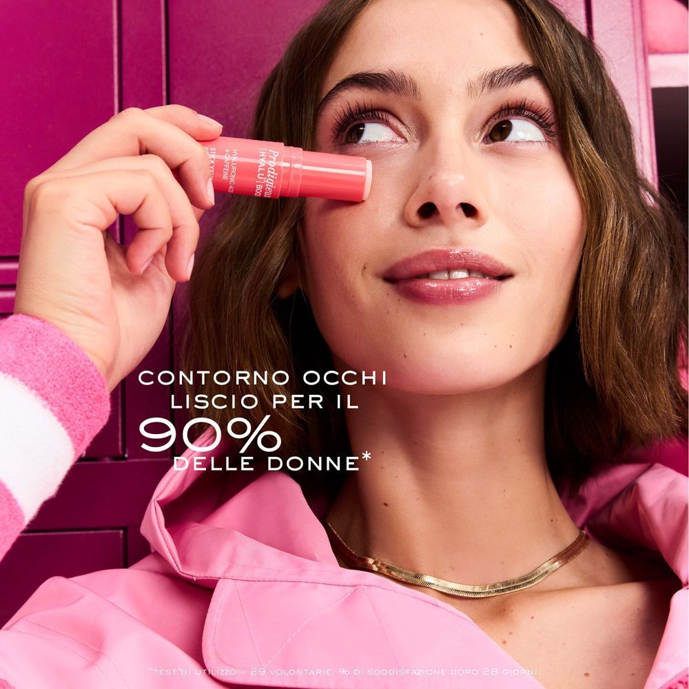 Una donna tiene uno stick contorno occhi Nuxe Prodigieuse [Hyalu] Boost vicino all'occhio.