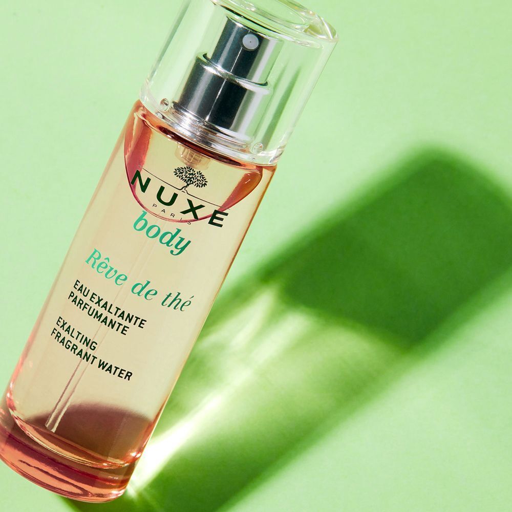 Un flacone Nuxe Rêve De Thé Eau Exaltante Parfumante su sfondo verde.