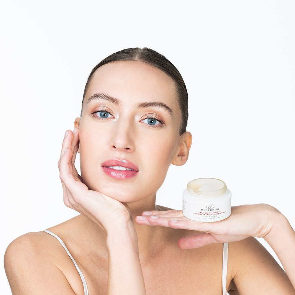 Donna con un vasetto di crema giorno multifunzionale Mitochon in mano.