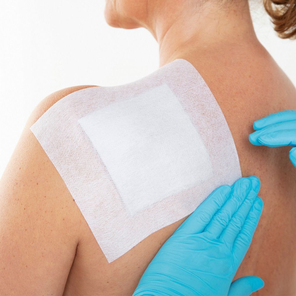 Leukoplast Fixomull Stretch applicato sulla spalla, da personale medico.