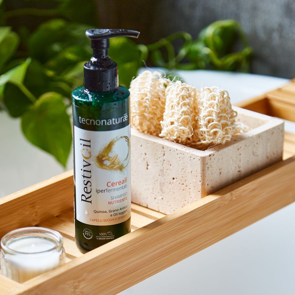Restivoil Tecnonaturae Shampoo Nutriente Cereali Iperfermentati su un vassoio di legno con accessori da bagno.