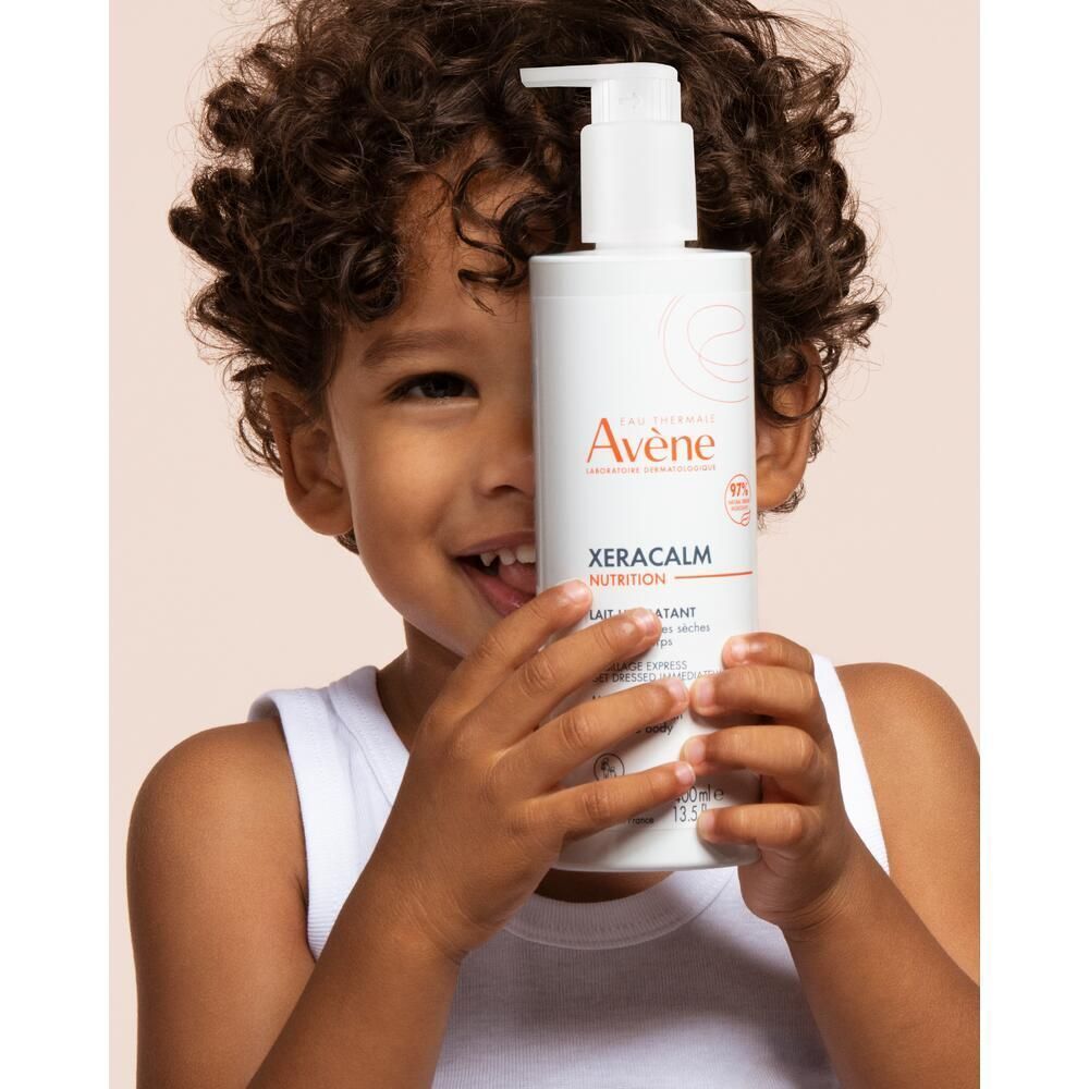 Un bambino tiene una bottiglia Eau Thermale Avène Xeracalm Nutrition con erogatore.