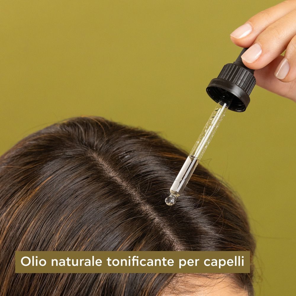 Gocce di olio per capelli APIVITA applicate sul cuoio capelluto con un contagocce.