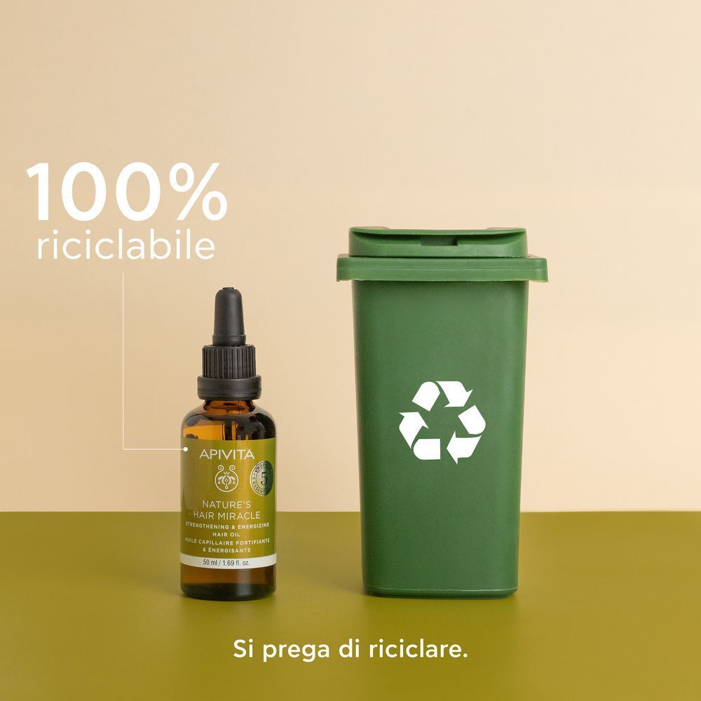Olio per capelli APIVITA accanto a un contenitore per il riciclaggio, riciclabile al 100%.