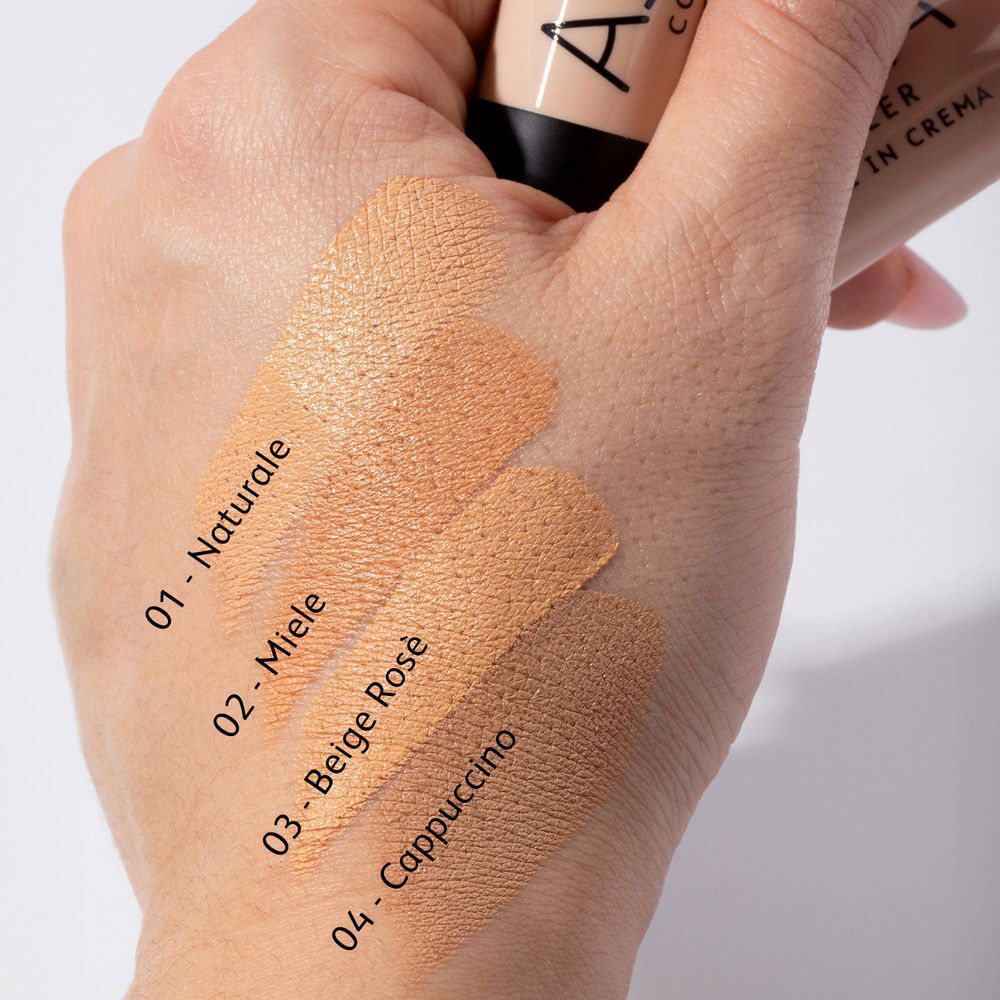 Mano con quattro swatch di correttore ASTRA in diverse tonalità: 01 Naturale, 02 Miele, 03 Beige Rosé, 04 Cappuccino.