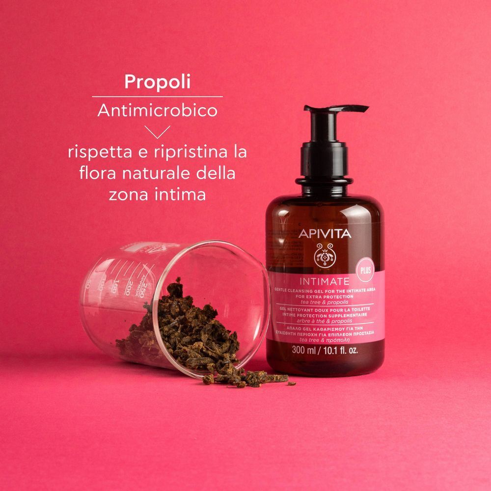 Gel detergente Apivita Intimate Plus accanto a boccioli di propoli in un bicchiere.