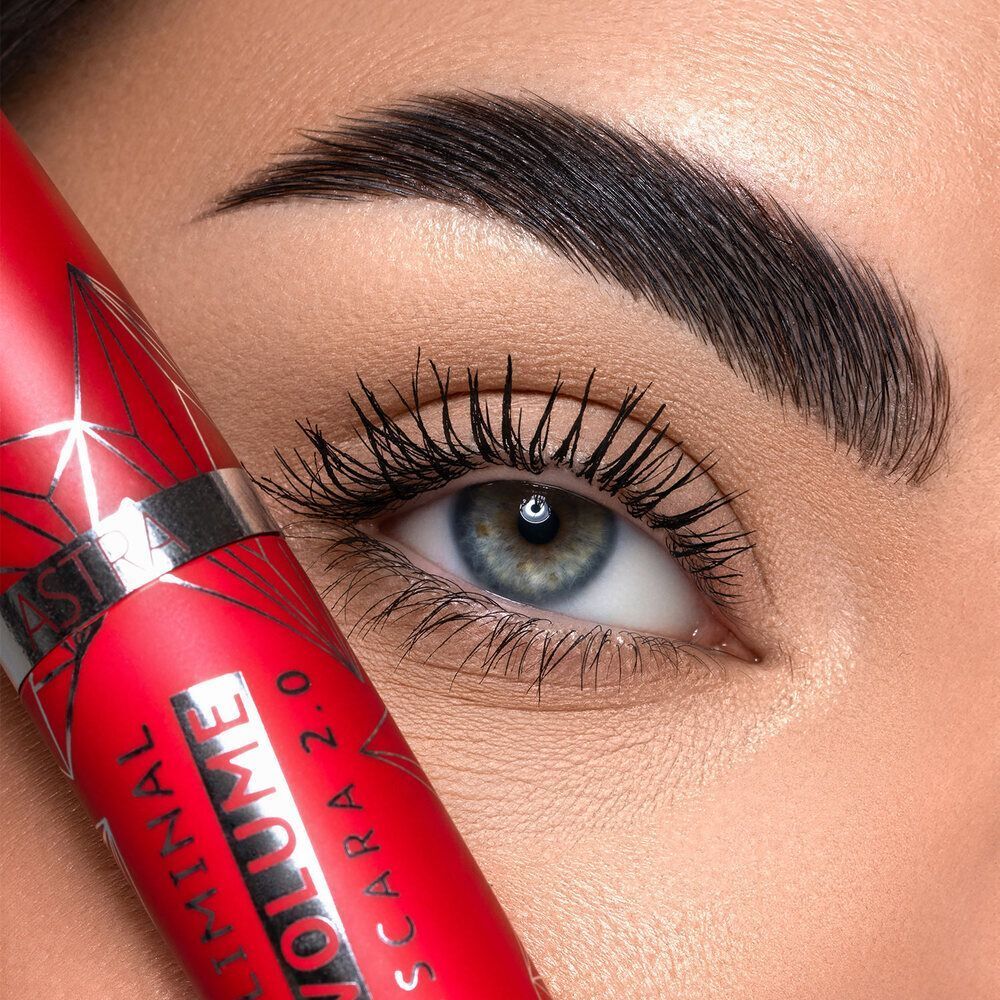 Un applicatore di mascara rosso accanto a un occhio, che enfatizza le ciglia.