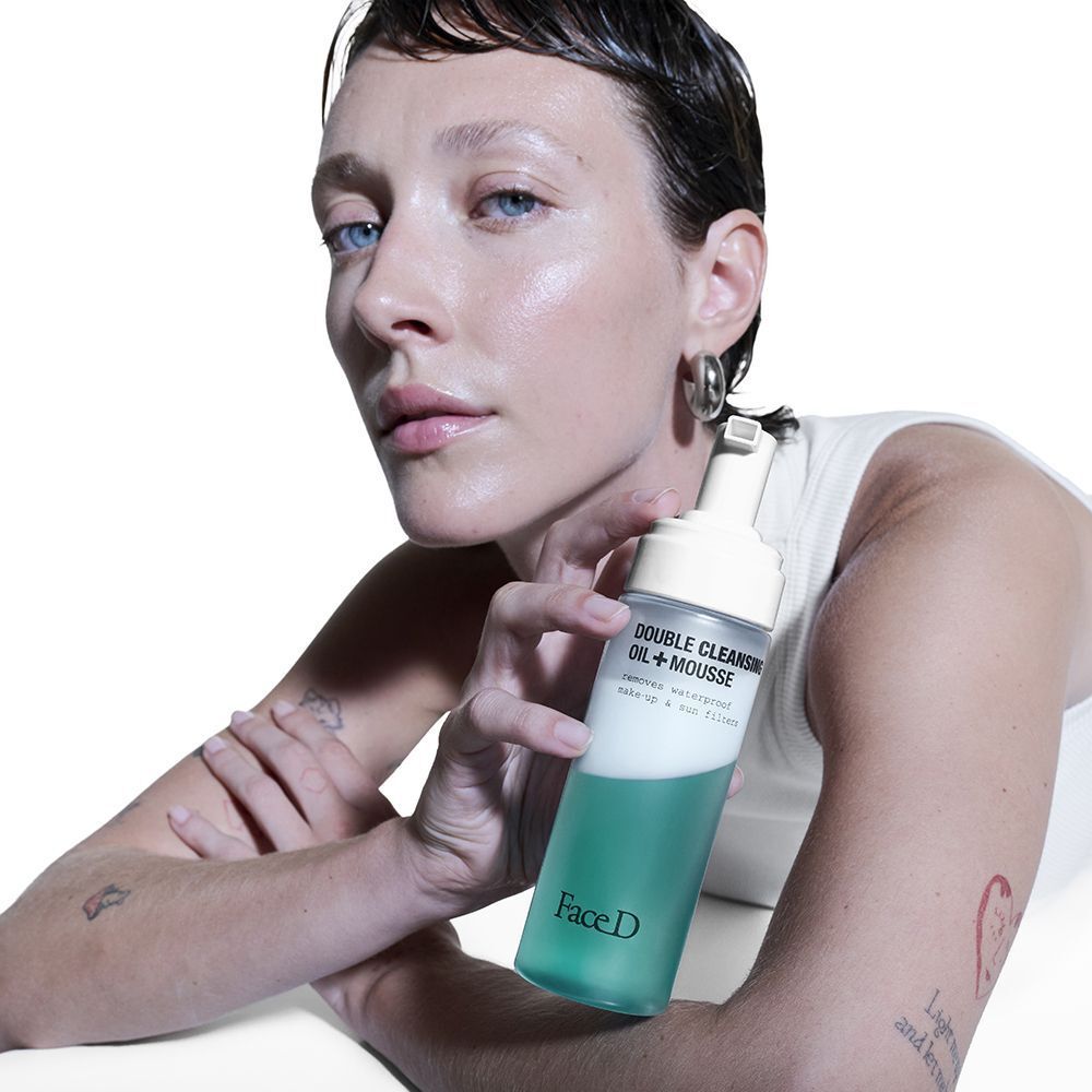 Donna che tiene in mano il detergente viso Face D Doppia Detersione Olio + Mousse con dispenser a pompa.
