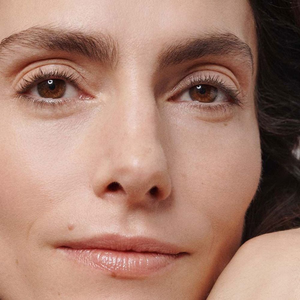 Primo piano di un viso con pelle impeccabile e trucco discreto.