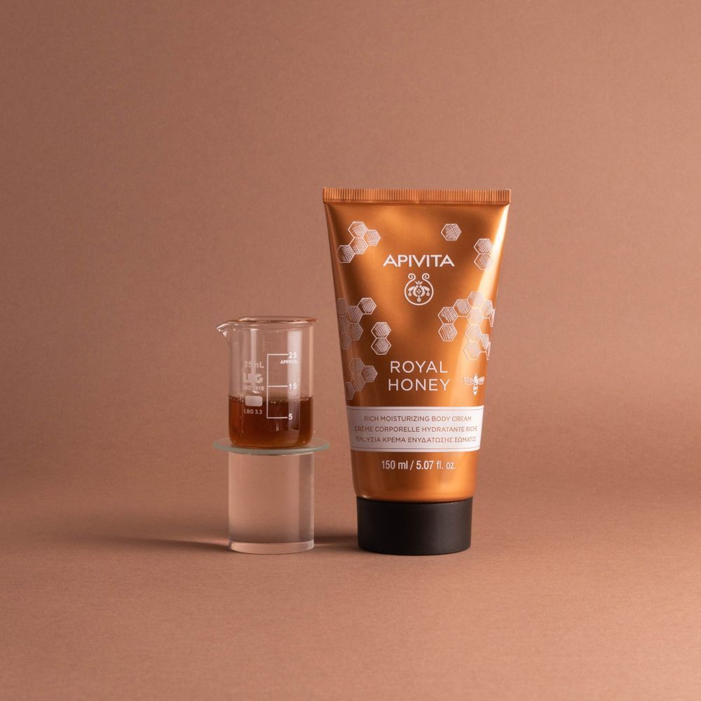Crema corpo APIVITA Royal Honey accanto a un becher con liquido.