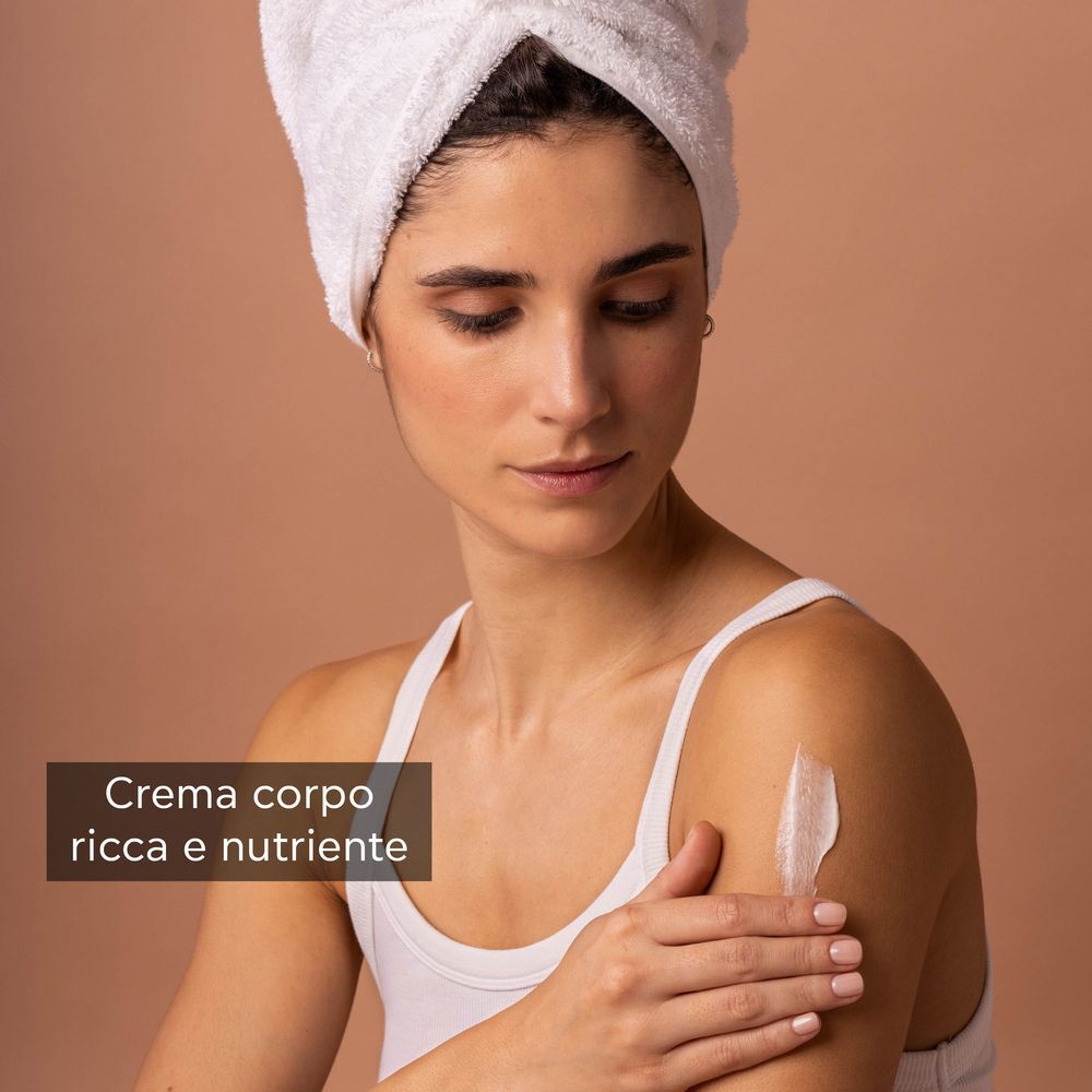 Donna con asciugamano applica crema corpo ricca e nutriente.