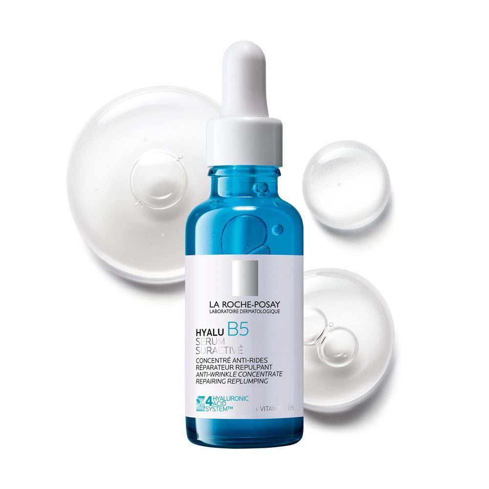 Un flacone di siero La Roche-Posay Hyalu B5 con contagocce, circondato da gocce di siero.