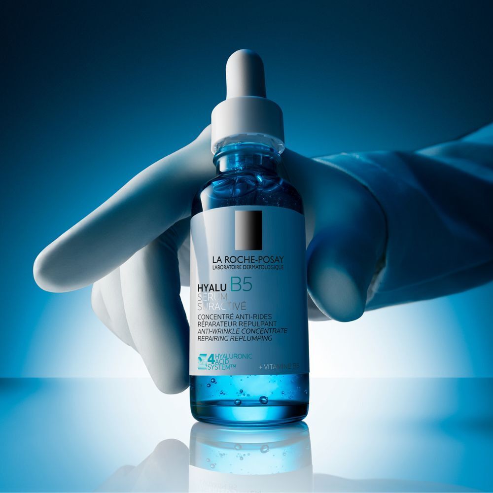 Una mano con guanto bianco tiene un flacone di siero La Roche-Posay Hyalu B5.