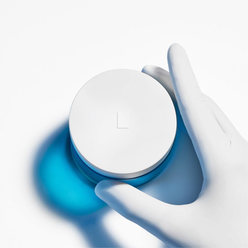 Mano con guanto tiene il coperchio di un vasetto La Roche-Posay Hyalu B5.