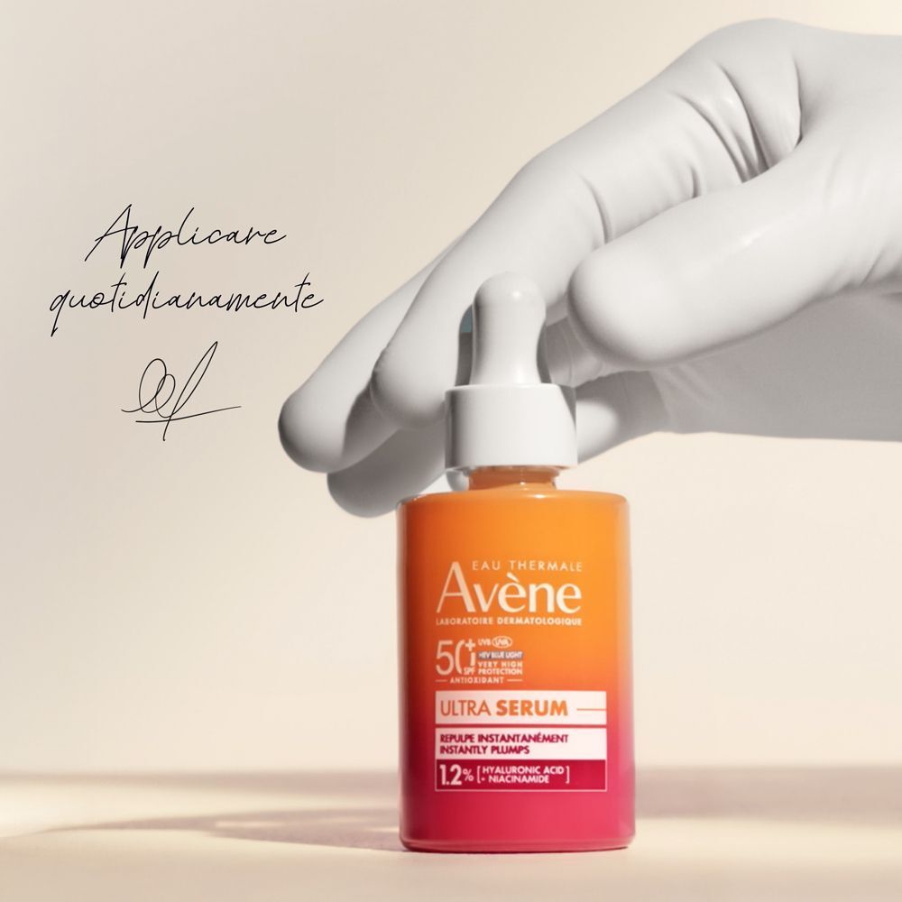Mano con guanto tiene flacone Eau Thermale Avène Ultra Siero SPF50+.