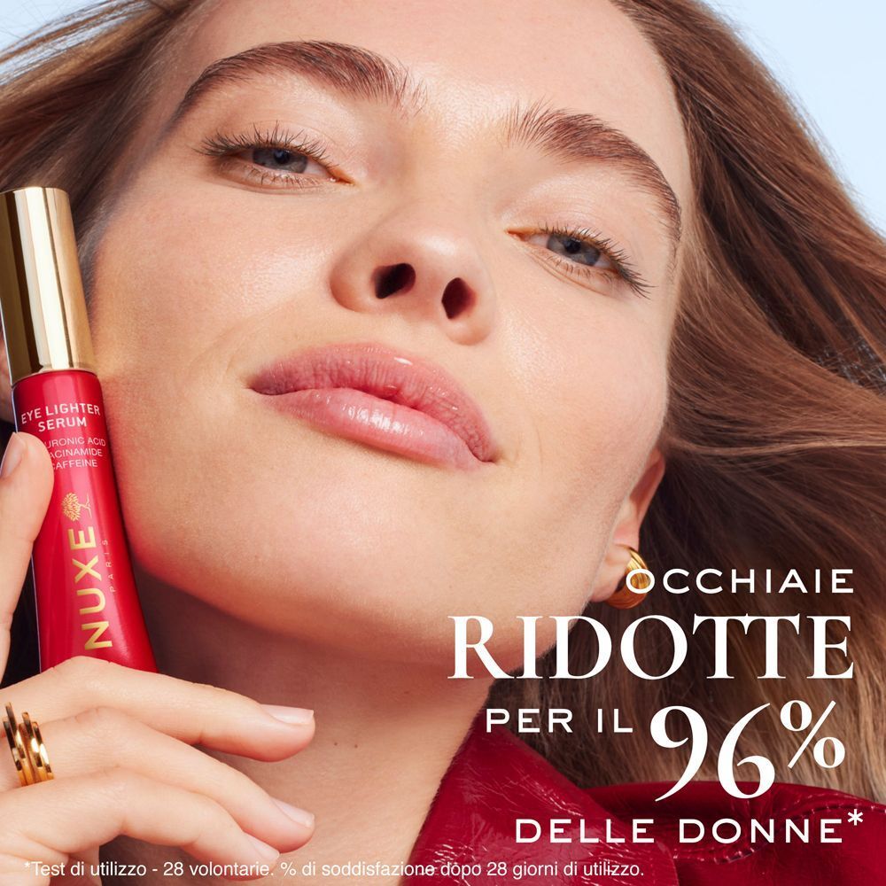 Una donna tiene un tubetto di Nuxe Eye Lighter Serum davanti al viso.
