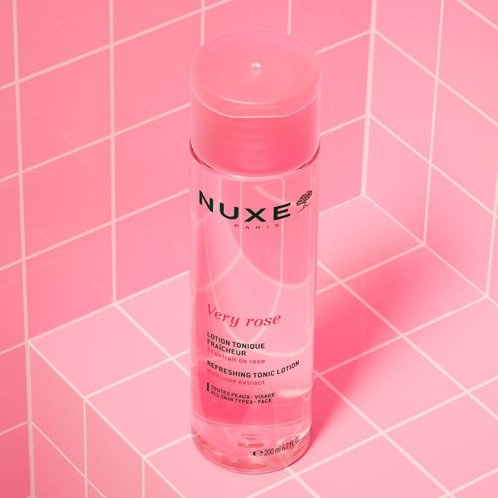 Un flacone di tonico rinfrescante Nuxe Very Rose su una superficie piastrellata rosa.