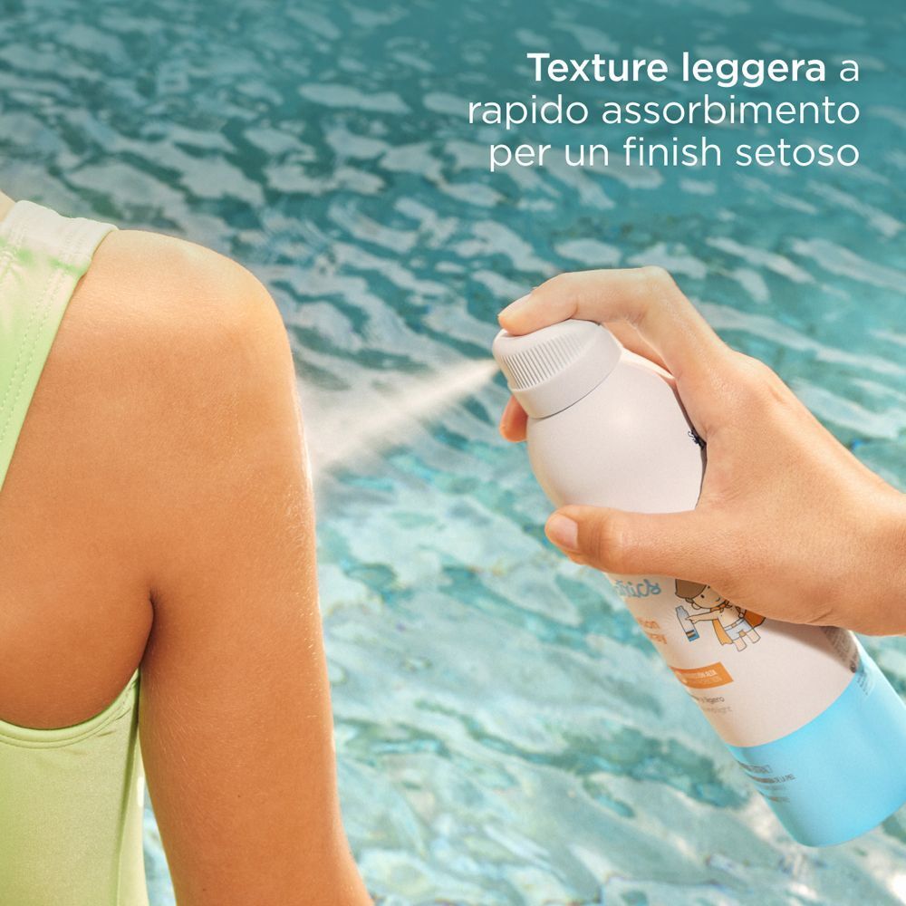 Una mano spruzza ISDIN Fotoprotector Pediatrics Transparent Spray SPF 50 sulla pelle.