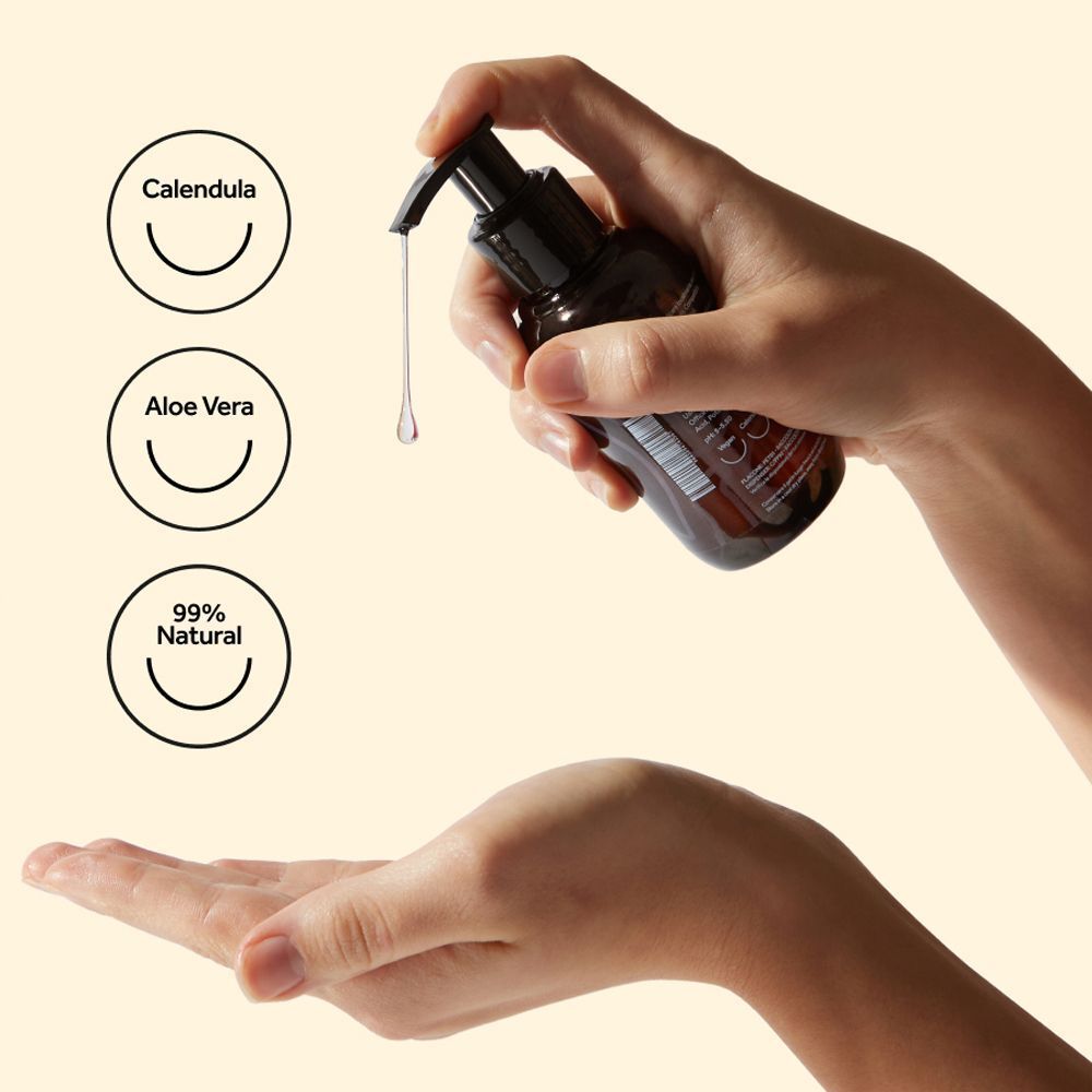 Mano preme il dispenser, gocce di lubrificante cadono nel palmo. Calendula, Aloe Vera, 99% naturale.