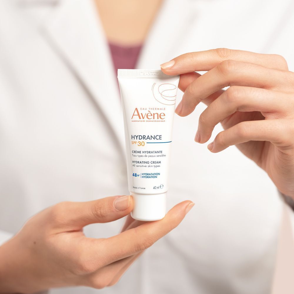 Mani che tengono la Crema Idratante SPF30 Hydrance Eau Thermale Avène, 40ml.