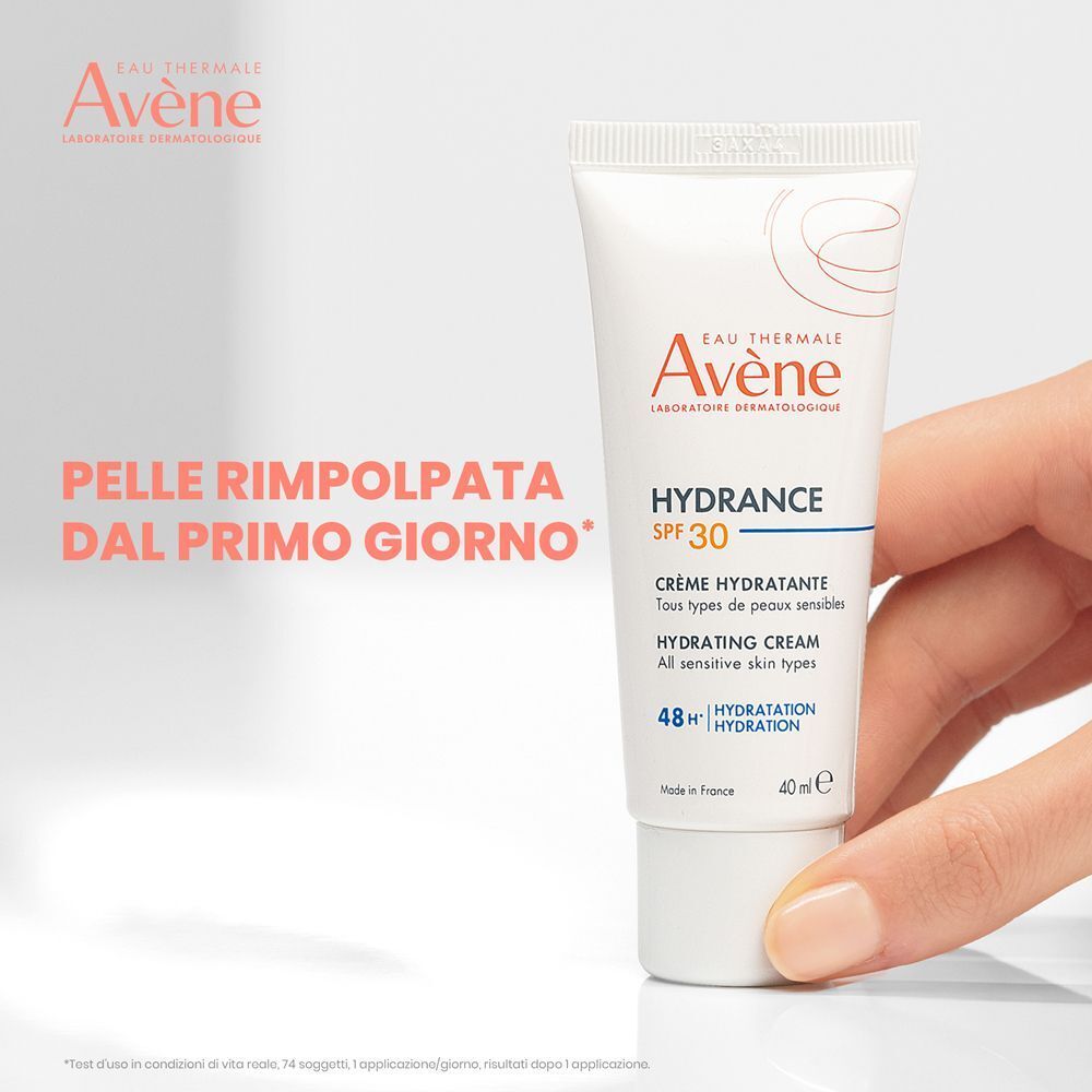 Mano che tiene Eau Thermale Avène Hydrance SPF30 Crema Idratante.