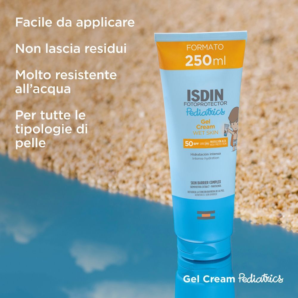 Tubo ISDIN Fotoprotector Gel Cream Pediatrics SPF50 sulla spiaggia con riflesso nell'acqua.
