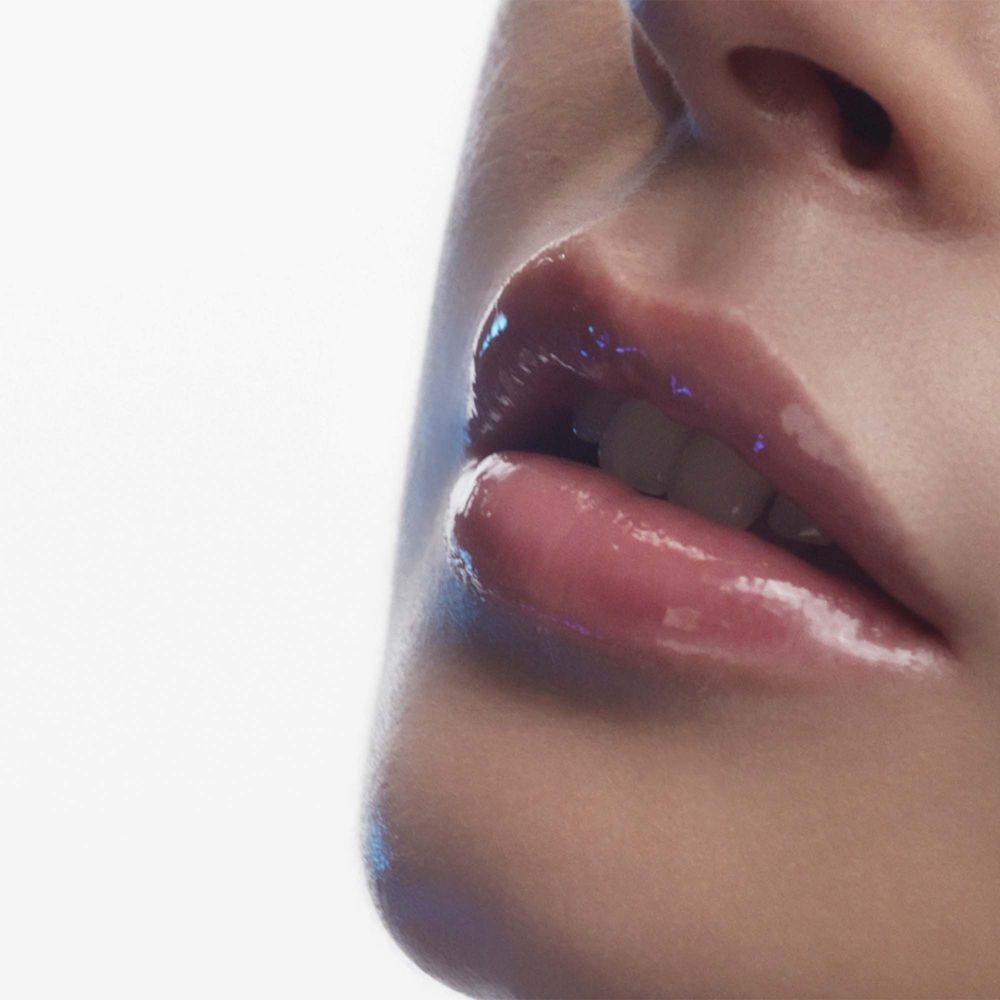 Primo piano di una donna con labbra piene e lucide e un tocco di blu.