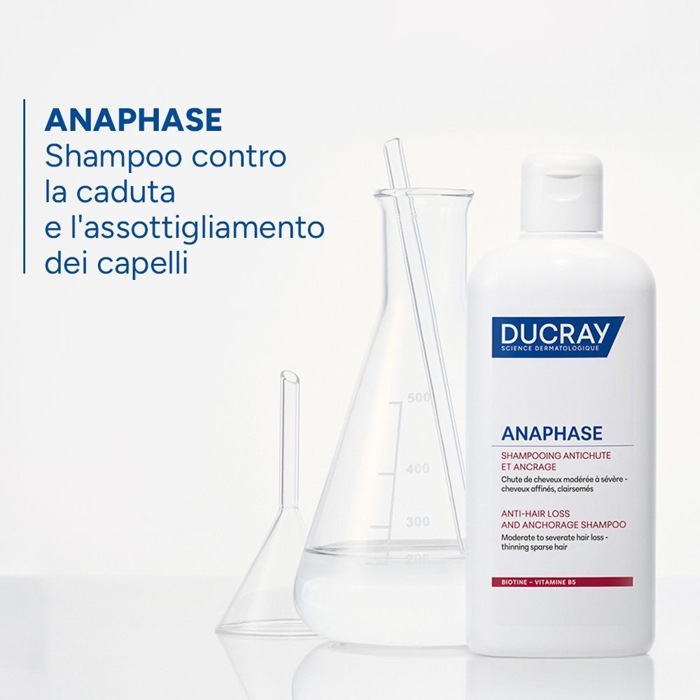Un flacone di Ducray Anaphase+ Shampoo accanto a vetreria da laboratorio.