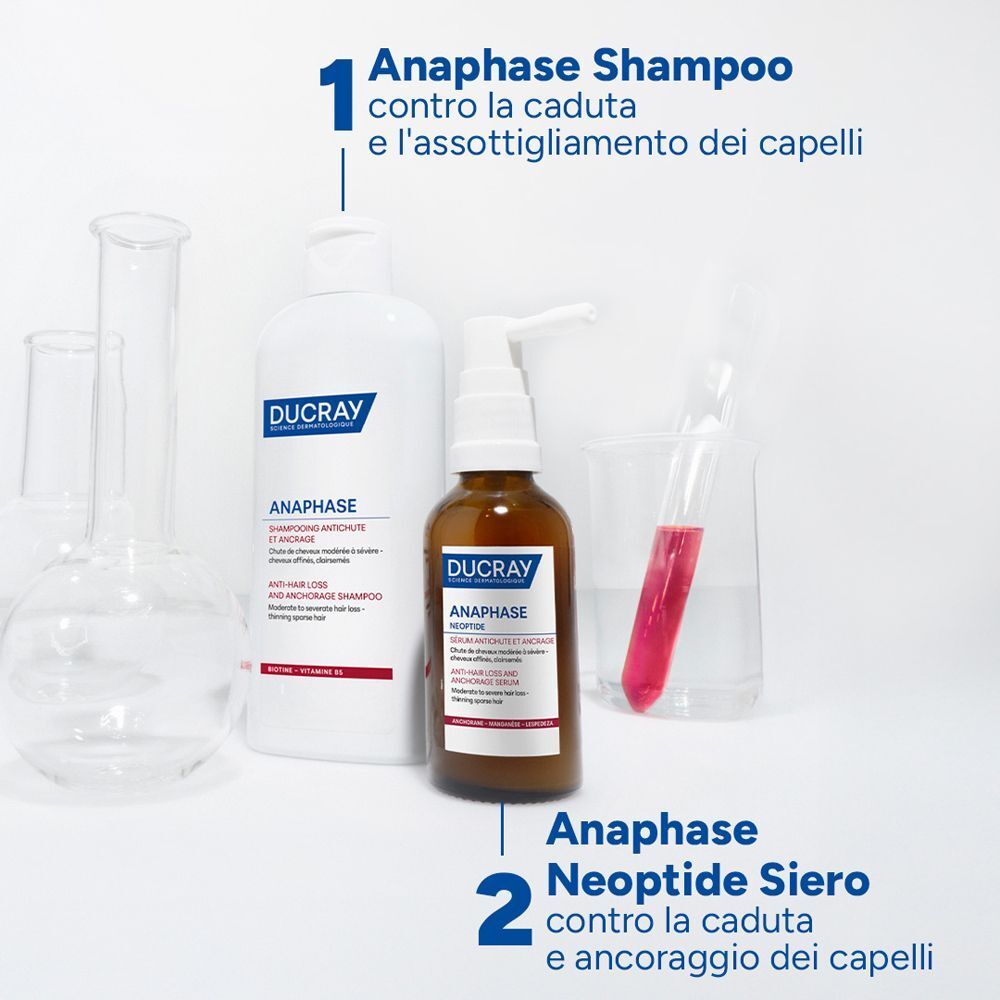 Ducray Anaphase+ Shampoo e Siero Neoptide accanto a vetreria da laboratorio.