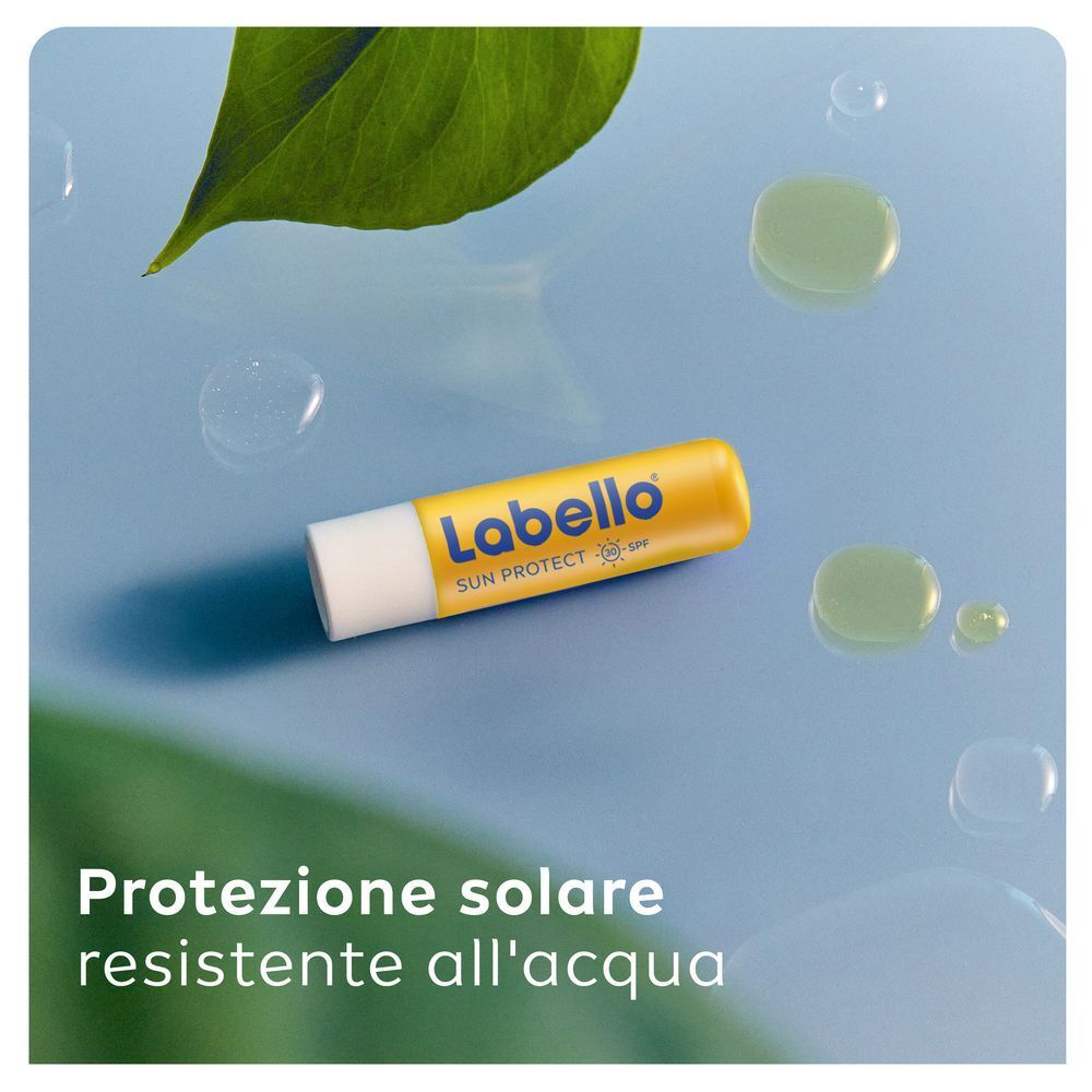 Balsamo labbra Labello Sun Protect SPF30 su sfondo blu con gocce d'acqua.