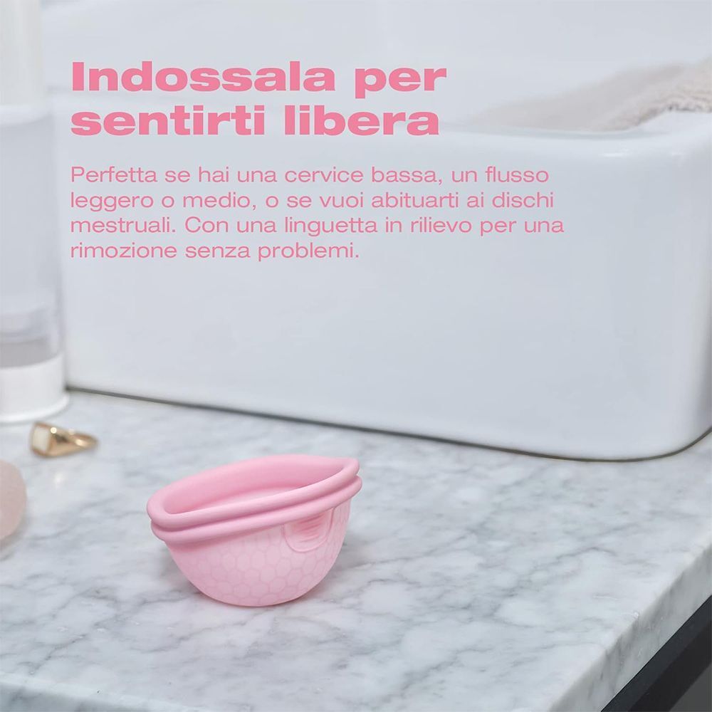 Coppetta mestruale rosa con texture a nido d'ape su una superficie di marmo.