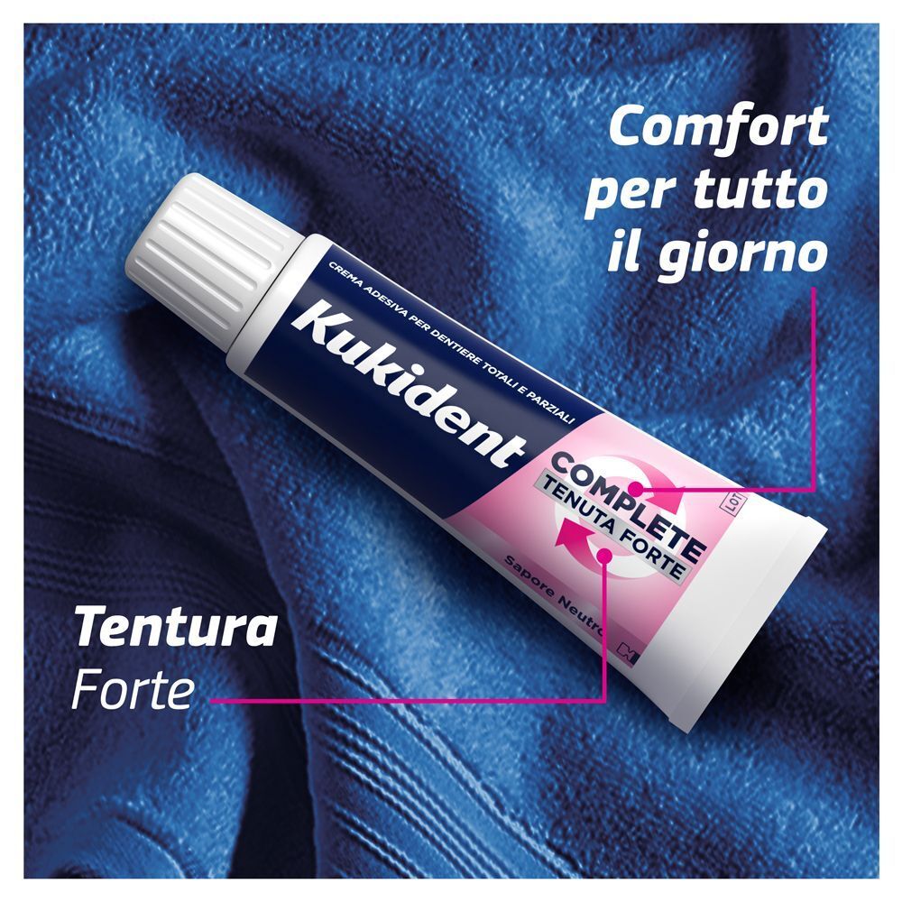 Un tubetto di crema adesiva Kukident Complete appoggiato su un asciugamano blu.