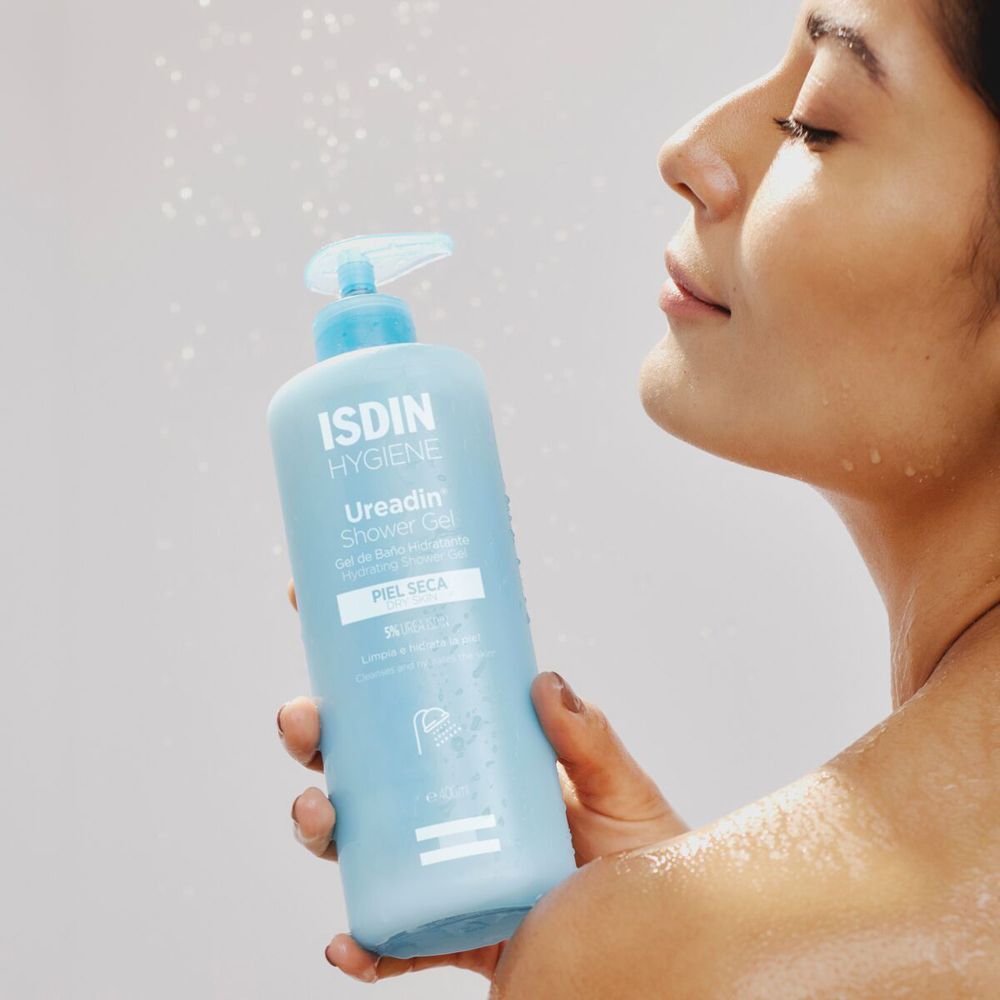 Una donna tiene il gel doccia ISDIN Ureadin sotto la doccia.